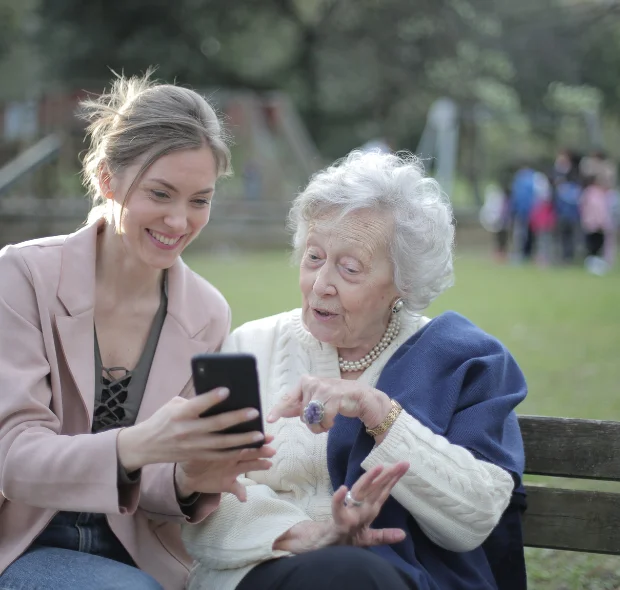 Young Lady showing an elderly lady how to use a seniors smartphone